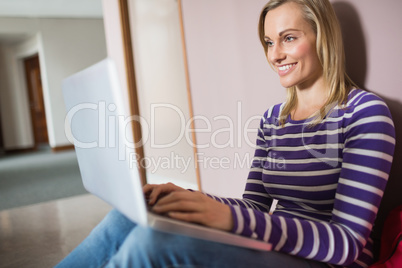 Female student smiling while using laptop