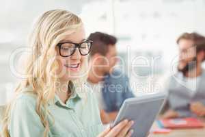 Happy woman wearing eyeglasses holding digital tablet
