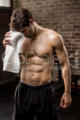 Muscular man wiping his face with towel