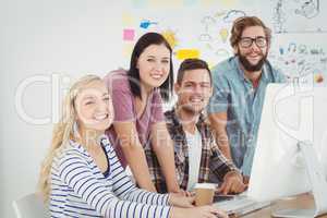 Portrait of smiling business professionals working at computer d