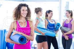 Woman smiling while holding exercise mat