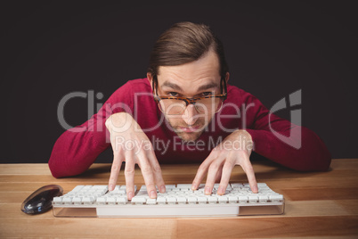 Man wearing eye glasses typing on computer keyboard