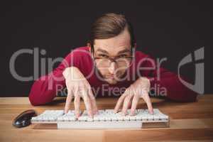 Man wearing eye glasses typing on computer keyboard