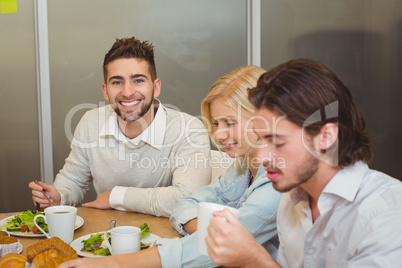 Smiling businessman with colleagues having snacks