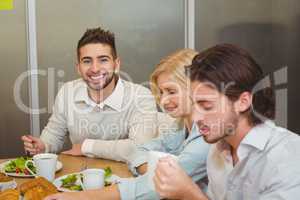 Smiling businessman with colleagues having snacks