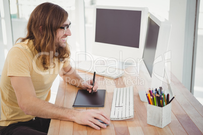 Happy hipster with graphics tablet looking at computer