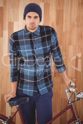 Portrait of hipster standing with bicycle