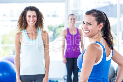 Portrait of cheerful woman with friends at fitness center