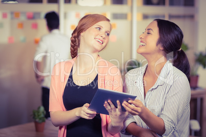 Happy businesswomen using digital tablet in office