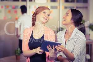 Happy businesswomen using digital tablet in office