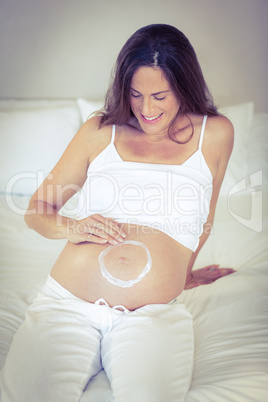 Happy woman making circle with lotion on belly