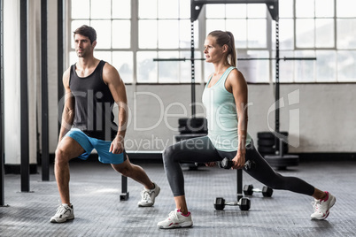 Male trainor with woman using dumbbells exercising