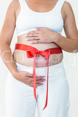 Midsection of pregnant woman with a red ribbon around her bump