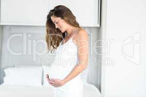 Happy pregnant woman standing in bedroom
