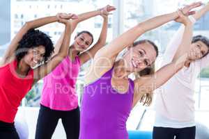Portrait of smiling women exercising with arms raised