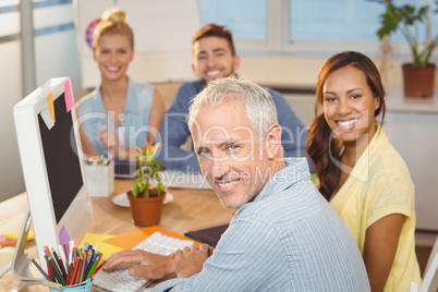Business people sitting by desk with computer