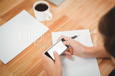 Hipster using smartphone at desk in office