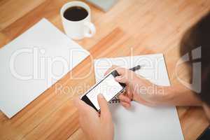 Hipster using smartphone at desk in office