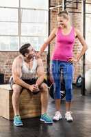 Standing and sitting muscular couple looking at each other