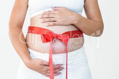 Close-up of pregnant woman with red ribbon