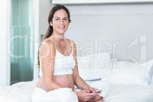 Portrait of pregnant woman sitting with smartphone
