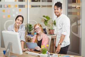 Portrait of smiling business people pointing towards computer in