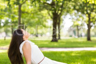 Side view of brown hair woman sitting on grass
