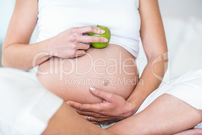 Midsection of woman with Granny smith on belly