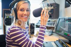 Happy young female radio host broadcasting in studio