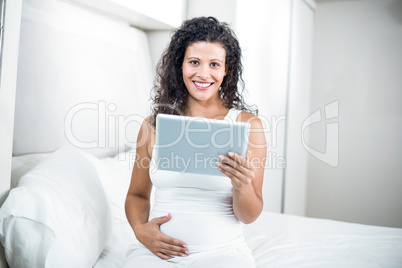 Portrait of beautiful pregnant woman using digital tablet