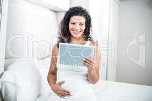 Portrait of beautiful pregnant woman using digital tablet