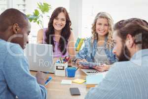 Portrait of smiling business people with men working at desk