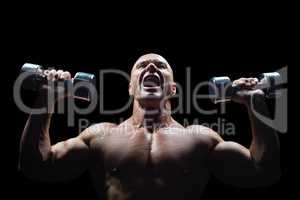 Aggressive bodybuilder lifting bumbbells