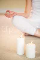 Low section of woman in yoga pose with illuminated candles