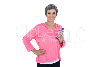 Cheerful mature woman holding bottle while listening music