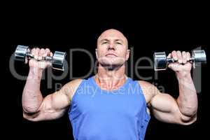 Muscular man in vest lifting dumbells
