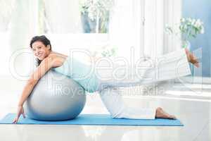 Smiling pregnant woman stretching with exercise ball