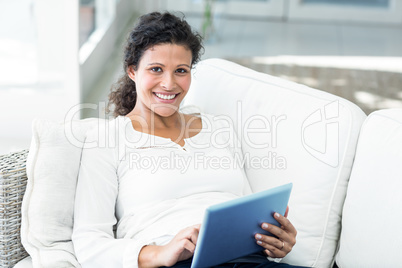 Portrait of happy woman with tablet on sofa