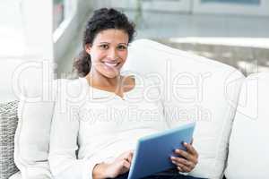 Portrait of happy woman with tablet on sofa