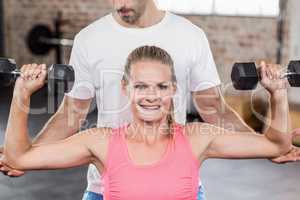 Fit woman lifting dumbbells with trainer