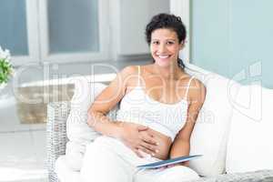 Portrait of happy woman sitting on sofa with tablet