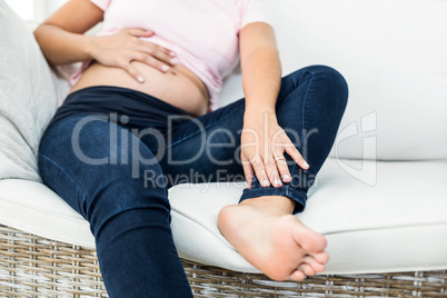 Low section of pregnant woman touching belly