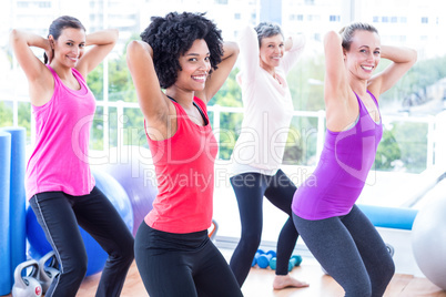 Portrait of smiling women exercising with hands behind head
