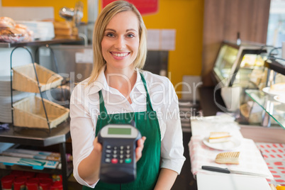 Happy female shop owner holding credit card reader
