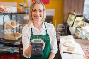 Happy female shop owner holding credit card reader