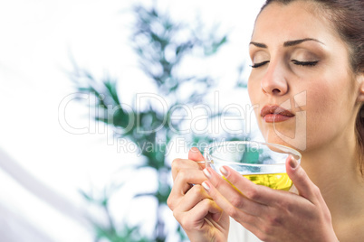 Woman smelling herbal tea with eyes closed