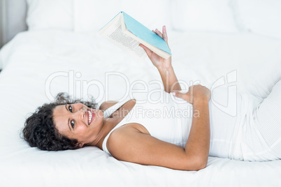 Portrait of smiling pregnant woman reading book