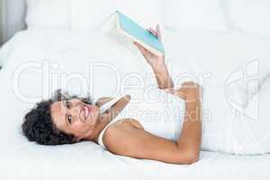 Portrait of smiling pregnant woman reading book