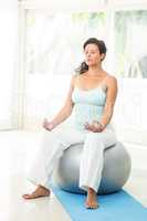 Peaceful blonde pregnant woman sitting on exercise ball