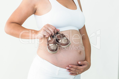 Pregnant woman holding baby shoes